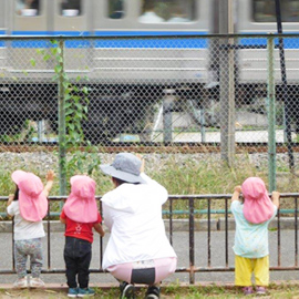 先生といっしょに電車が通るのを眺める園児たち